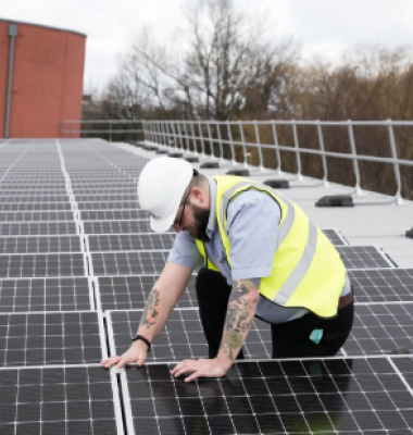 Photograph of workman on roof of Kirkby Leisure Centre, installing solar panels