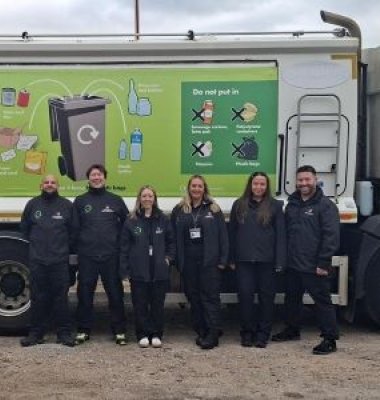 Photograph of 6 people from the Recycling Engagement team stood in front of recycling wagon