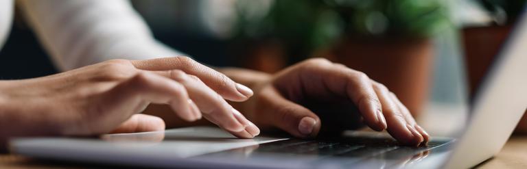 A photograph of a person typing on a laptop