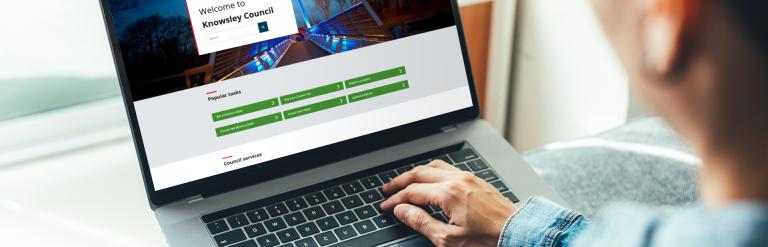 A photograph of a person navigating the Knowsley Council website on a laptop