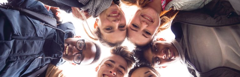A photograph of six young people gathered in a circle smiling